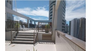 Eine Dachterrasse mit Blick auf umliegende Gebäude, einer Treppe und einem Geländer.