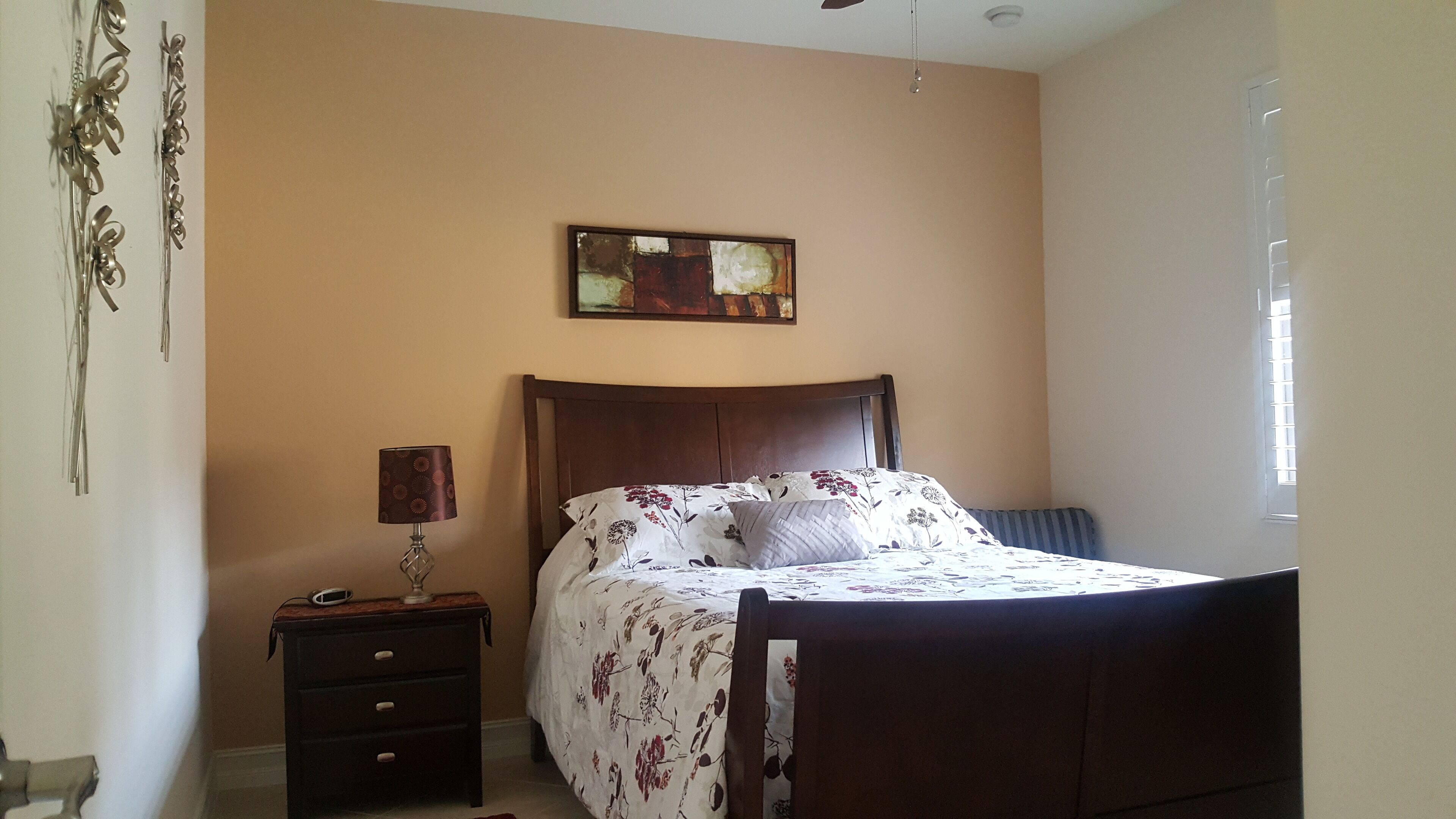 A bedroom with a bed, a nightstand, a lamp, and a painting on the wall.