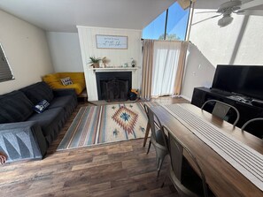 A living room with a fireplace, a sofa, a dining table, and a TV.