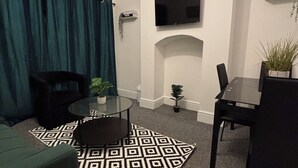 Ein modernes Wohnzimmer mit einer Couch, einem Couchtisch, einem an der Wand befestigten Fernseher und einem kleinen Kamin.