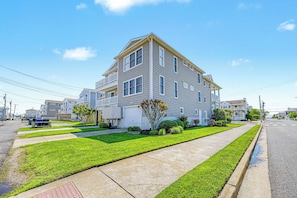 A two-story residential building with a garage, a well-maintained lawn, and a clear sky. - Gorgeous 5BR 3BA Home, close to beach, Town + playground; full linen service (Ocean City)
