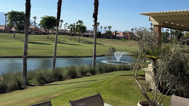 Een golfbaan met palmbomen, een vijver en een paviljoen.