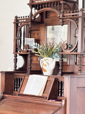 A wooden piano with sheet music, a decorative vase with plants, and a mirror above. - Historic Beaufort Estate - Near Downtown Beaufort & Parris Island (Beaufort)