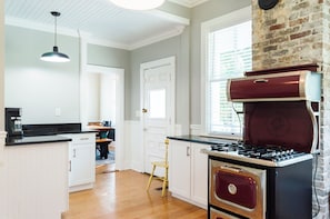 A kitchen with white cabinetry, a gas stove, and a brick wall. - Historic Beaufort Estate - Near Downtown Beaufort & Parris Island (Beaufort)