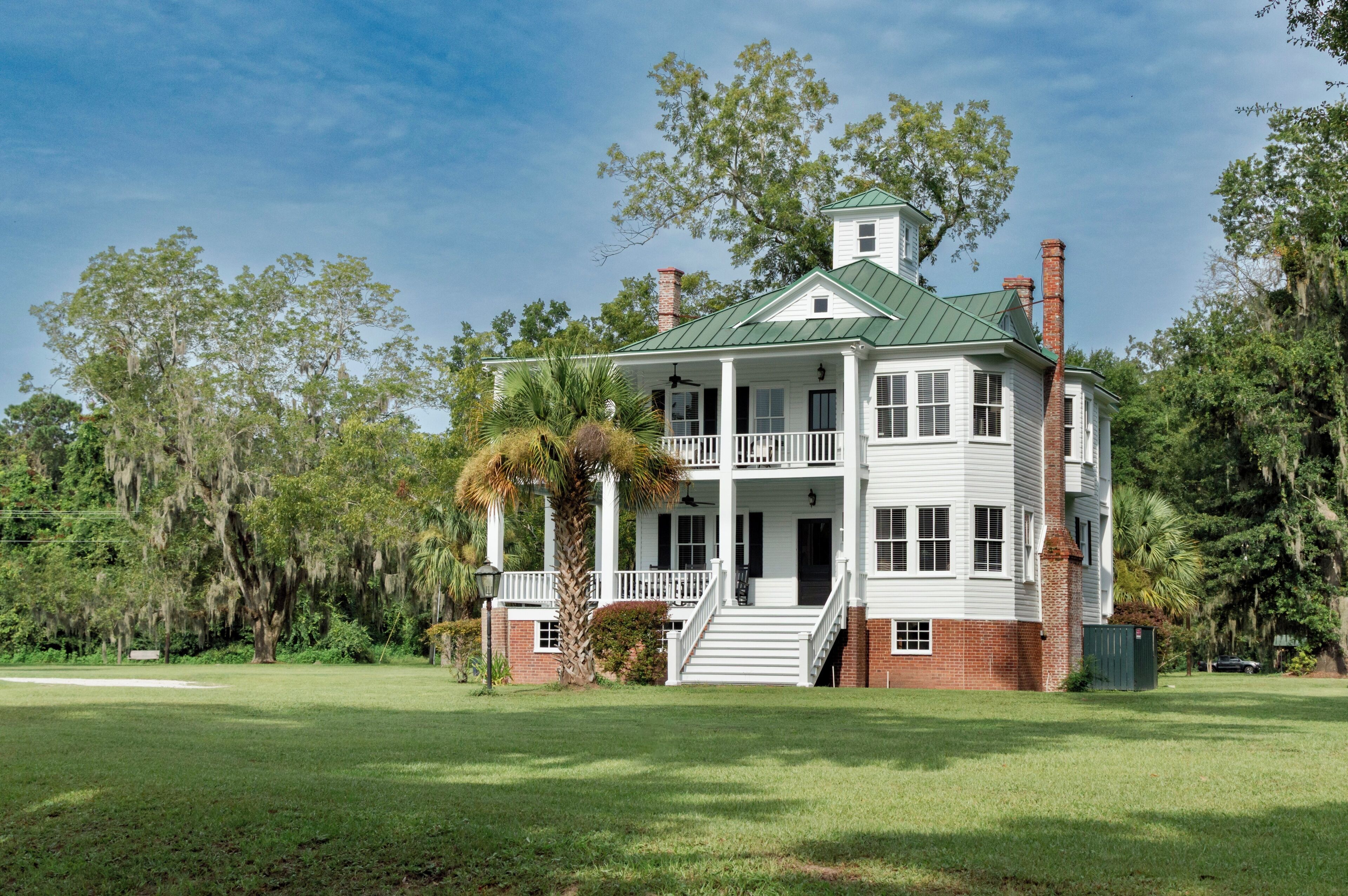 A two-story house with a green roof, white exterior, and a front porch.