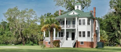 A two-story house with a green roof, white exterior, and a front porch.