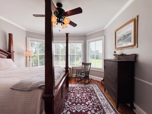 A four-poster bed with a wooden headboard, a ceiling fan, and a window with blinds. - Historic Beaufort Estate - Near Downtown Beaufort & Parris Island (Beaufort)