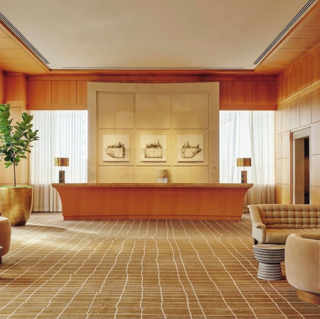 A reception area with a wooden reception desk, a large potted plant, and framed artwork on the wall.