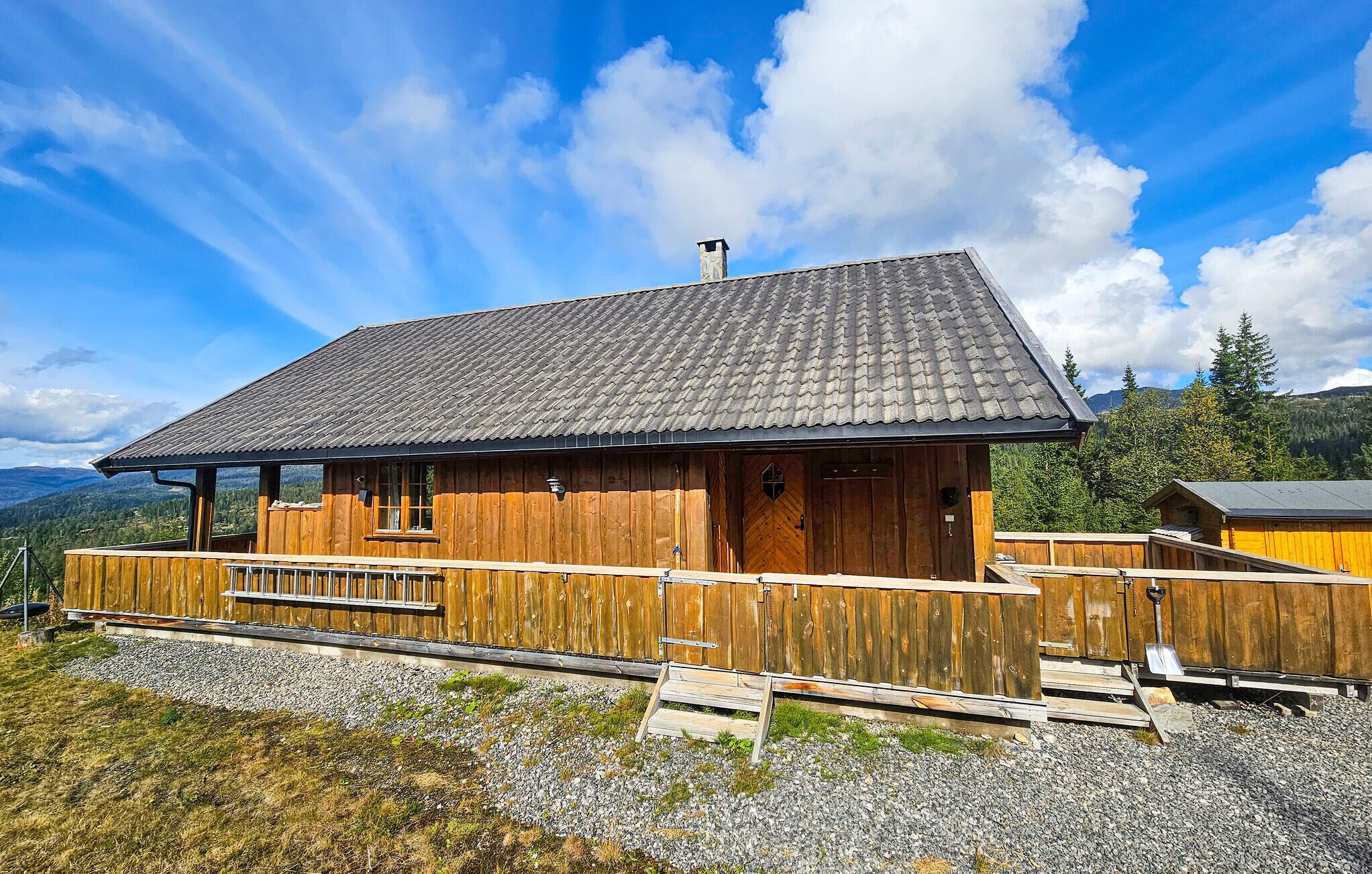 A wooden cabin with a sloped roof, a chimney, and a wooden deck.
