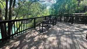 A wooden deck with chairs and a railing overlooking a body of water.