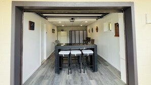 A covered patio area with a table and chairs, a ceiling fan, and a view into the house.