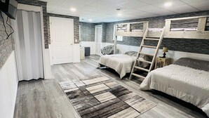 A bedroom with two bunk beds, a wooden floor, a patterned rug, and a TV mounted on the wall.