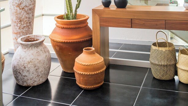 A modern interior with a staircase, terracotta pots, and woven baskets.