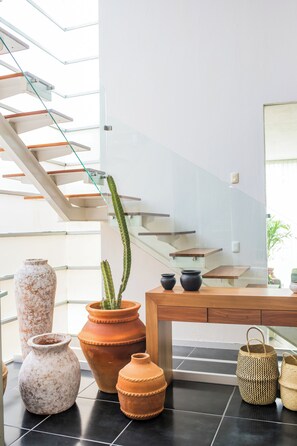 A modern interior with a staircase, terracotta pots, and woven baskets.