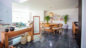 A modern dining area with a round wooden table, chairs, and a large potted plant.