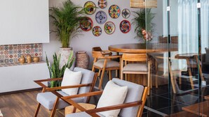 A modern living room with a glass partition, wooden furniture, and decorative plates on the wall.