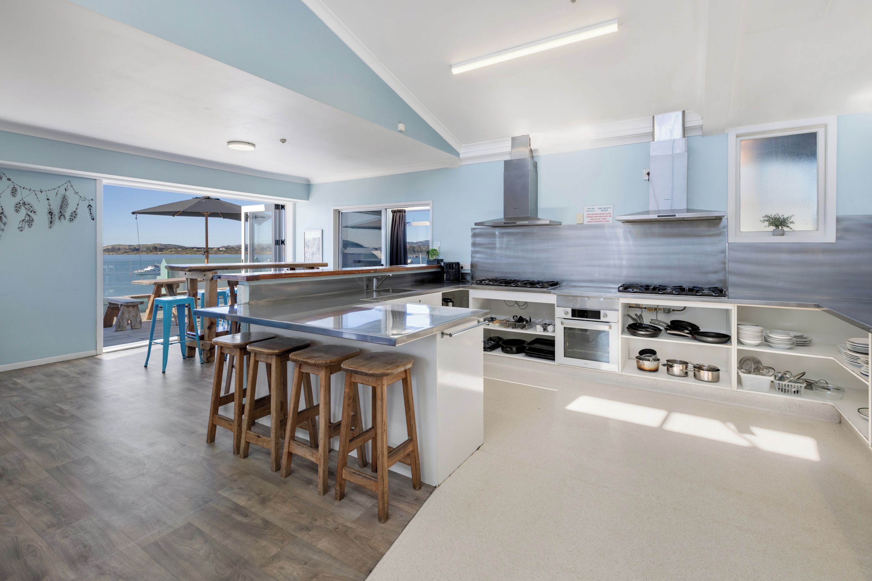 Een moderne keuken met een groot eiland, barstoelen en uitzicht op zee.