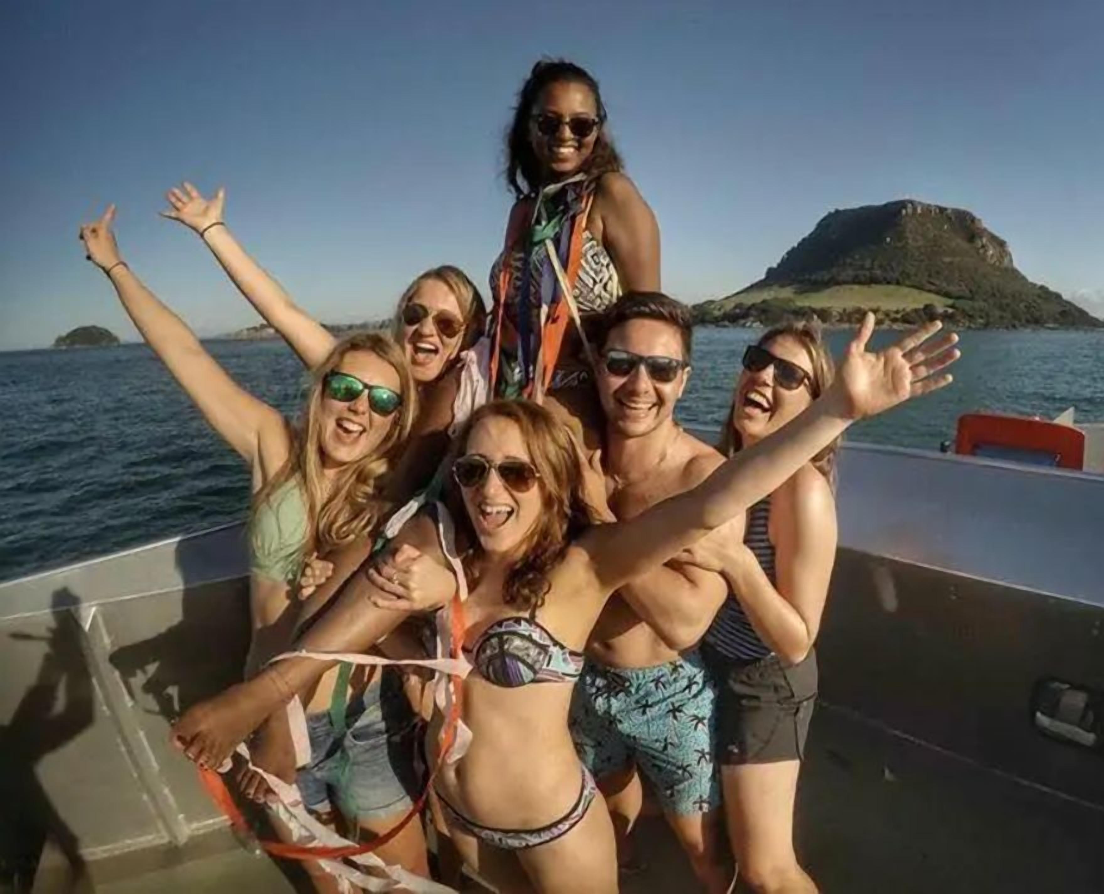 Um grupo de pessoas em um barco, com vista para uma ilha ao longe.