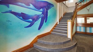 Una escalera con un mural de dos ballenas en la pared.