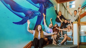 A group of people gathered around a mural of whales on a staircase. - Wanderlust NZ (Tauranga)