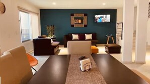 Ein modernes Wohnzimmer mit einem dunkelgrauen Sofa, einem Couchtisch und einem an der Wand befestigten Fernseher.