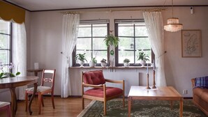 A cozy living room with a wooden table, a red chair, a green rug, and a window with plants. - Awesome home in Everöd with WiFi (Everöd)