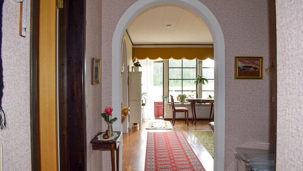 A hallway with an arched doorway leading to a dining area with a table and chairs, a red rug, and potted plants. - Awesome home in Everöd with WiFi (Everöd)