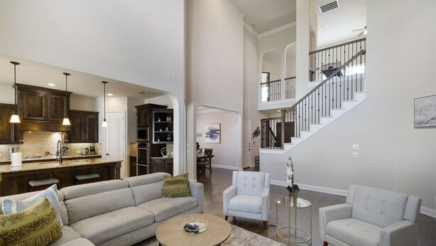 A spacious living room with a large sofa, two armchairs, and a coffee table. A kitchen with dark wooden cabinets and pendant lighting is visible in the background. - Spacious & Luxe, 5 Star Neighborhood, Movie Theater (Frisco)