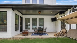 A covered patio with a fire pit, outdoor seating, and a TV mounted on the wall. - Spacious & Luxe, 5 Star Neighborhood, Movie Theater (Frisco)