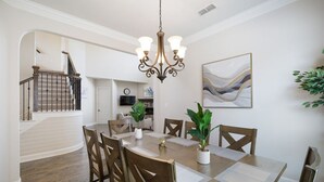 A dining area with a wooden table, chairs, a chandelier, and a painting on the wall. - Spacious & Luxe, 5 Star Neighborhood, Movie Theater (Frisco)