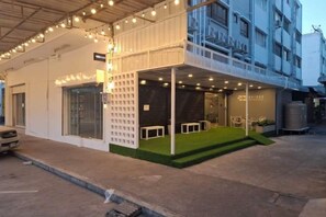 A hotel with a covered outdoor area, a car parked in front, and a building with multiple floors. - Bridge Donmueang (Bangkok)