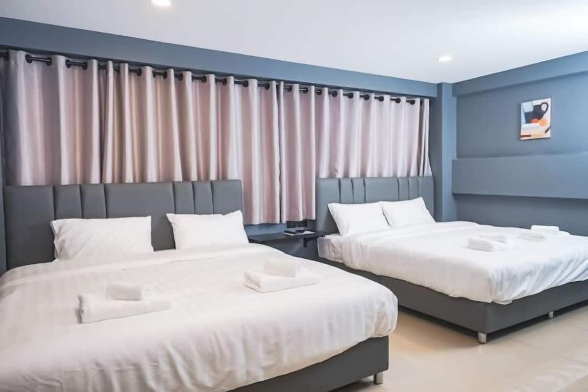 A hotel room with two beds, a headboard, curtains, a nightstand, and a wall-mounted artwork.