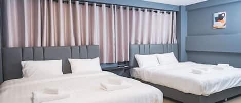 Habitación de hotel con dos camas, cabecero, cortinas, mesita de noche y una obra de arte colgada en la pared.