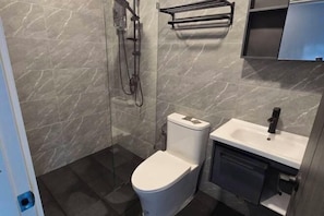 A modern bathroom with a toilet, sink, and shower.