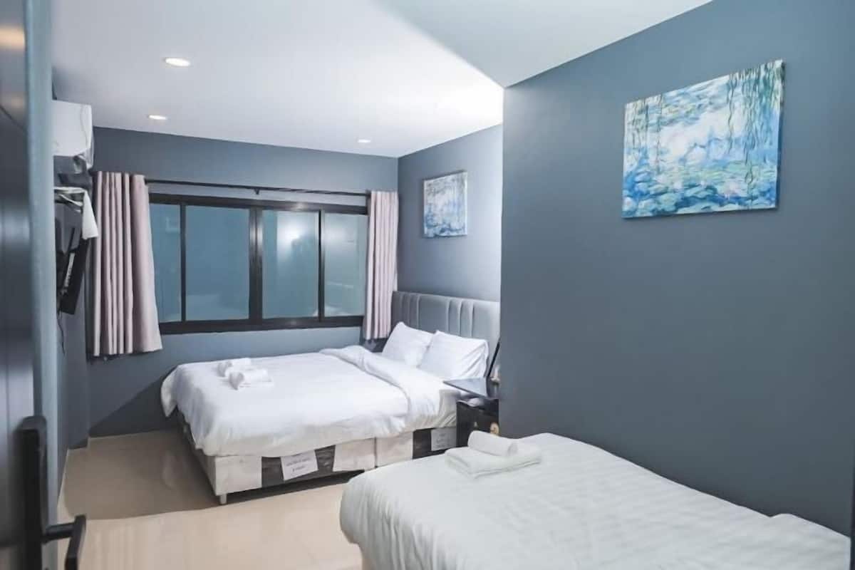 A modern hotel room with two beds, a large window, and a painting on the wall.