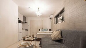 A compact living space with a kitchenette, a dining area, and a sofa. - Tengacyaya Ra Hotel (Osaka)