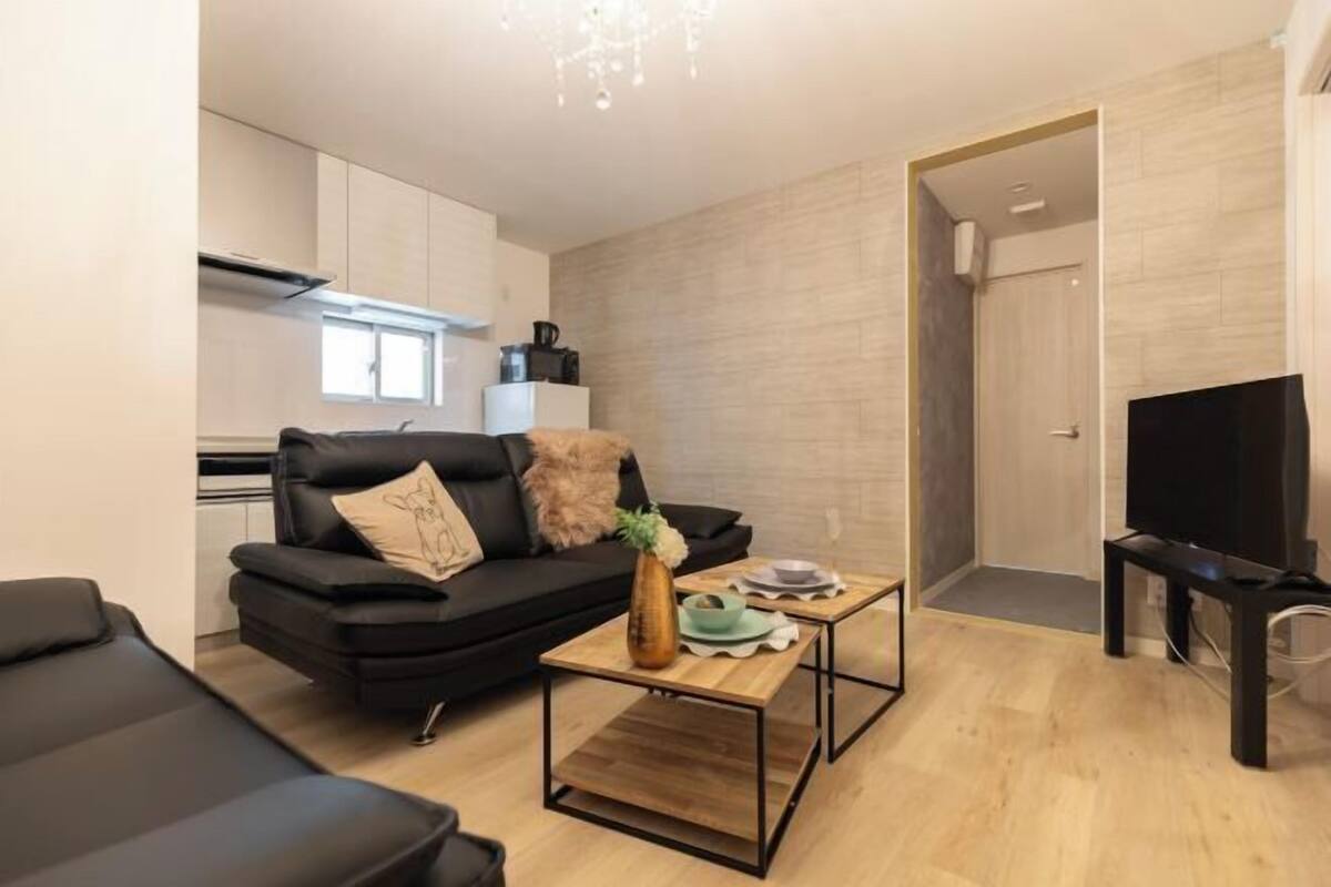 A modern living room with a black sofa, a coffee table, and a TV.