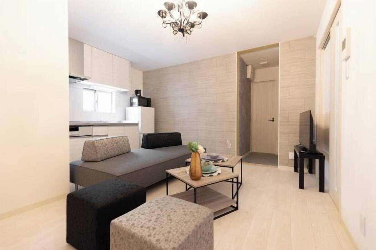 A modern living room with a sofa, ottoman, and a coffee table.