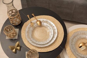 A table set with woven placemats, a glass vase, a glass candle holder, and a gold-colored decorative item. - Tengacyaya Ra Hotel (Osaka)