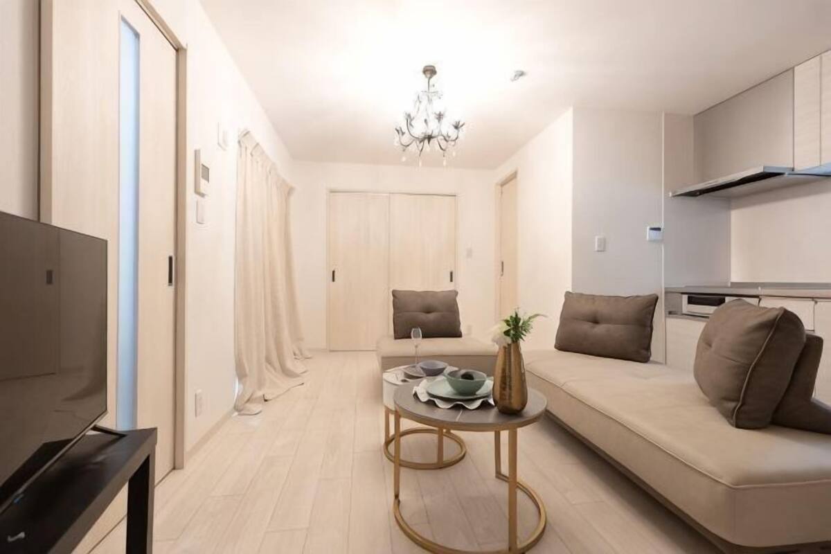 A modern living room with a sofa, a coffee table, a TV, and a chandelier.