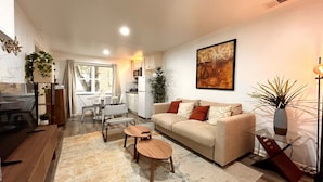 A modern living room with a sofa, coffee table, and dining area.