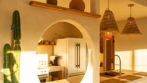 A kitchen with a central island, a refrigerator, and hanging pendant lights. - Sundara | Pool | Spa | Pickleball | Sauna | Games (Joshua Tree)