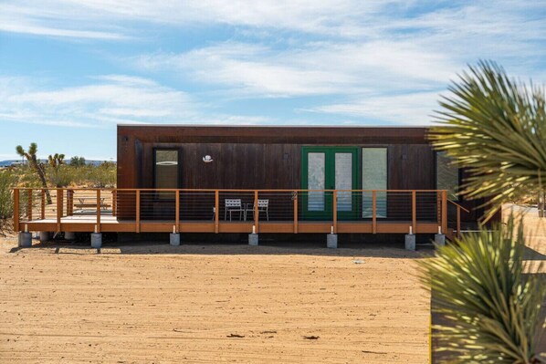 Un edificio moderno con terraza de madera, una puerta verde y un letrero con el número 2.