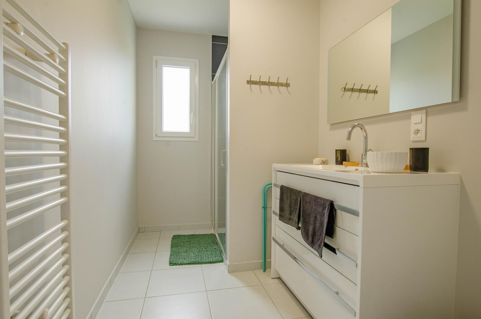 A bathroom with a white sink, a mirror, and a towel rack.
