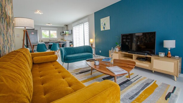 A modern living room with a yellow sofa, teal armchair, and a TV on a wooden stand. - Le Fairway - BREVIANDES (BREVIANDES)