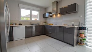 A modern kitchen with dark cabinets, a white dishwasher, and a window above the sink. - Le Fairway - BREVIANDES (BREVIANDES)