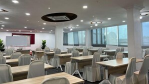 Una sala conferenze con diversi tavoli e sedie, una lavagna e ampie finestre.
