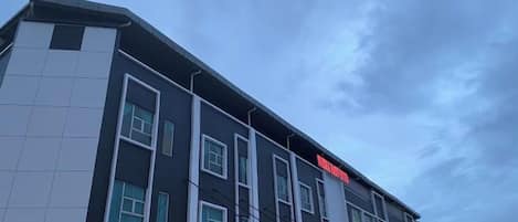 A modern building with a flat roof, large windows, and a prominent red sign.
