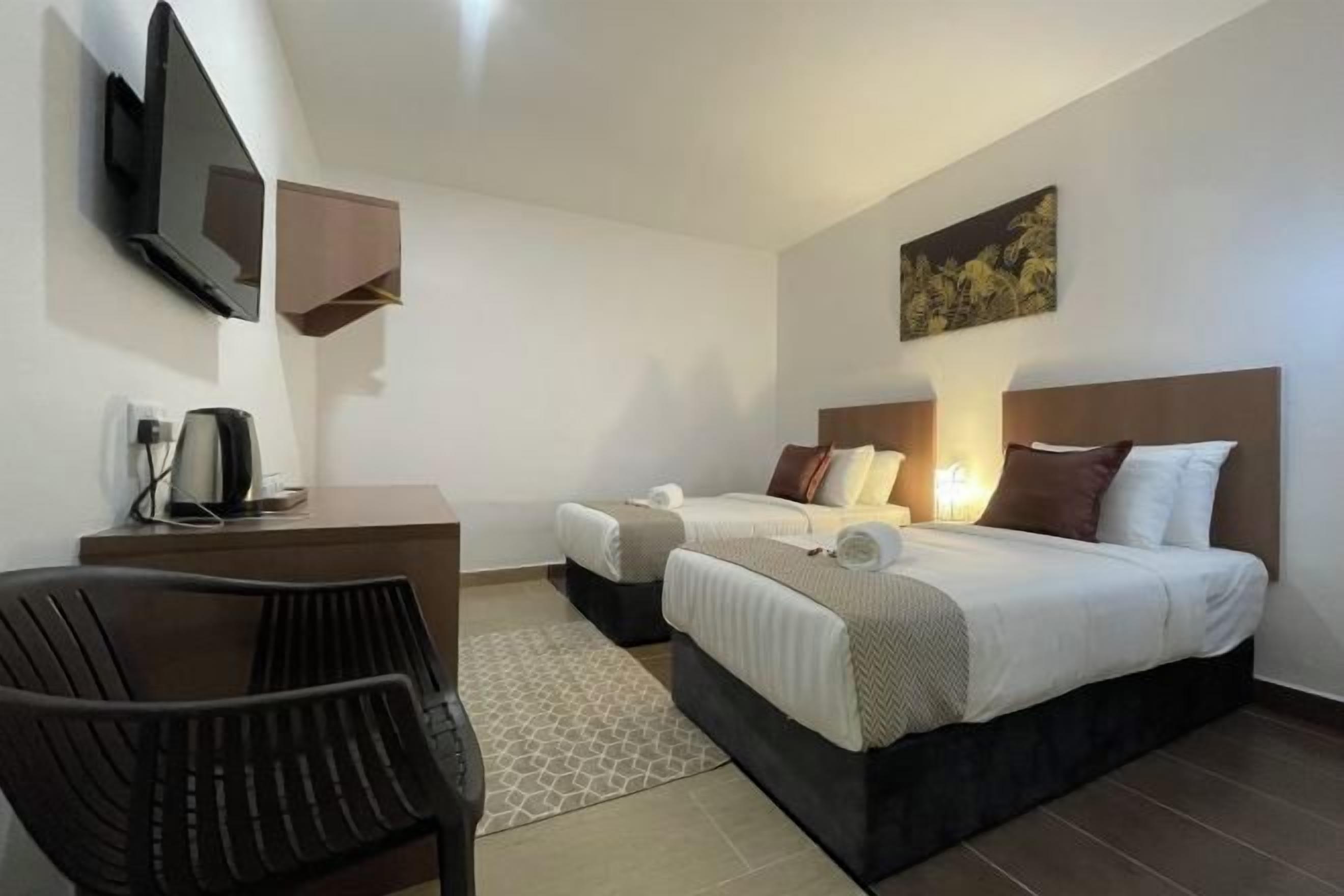Ein Hotelzimmer mit Bett, Schreibtisch, Stuhl, Fernseher und einem Bild an der Wand.