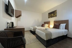 A hotel room with a bed, a desk, a chair, a TV, and a painting on the wall. - DSH Hotel (Kuala Kuantan)